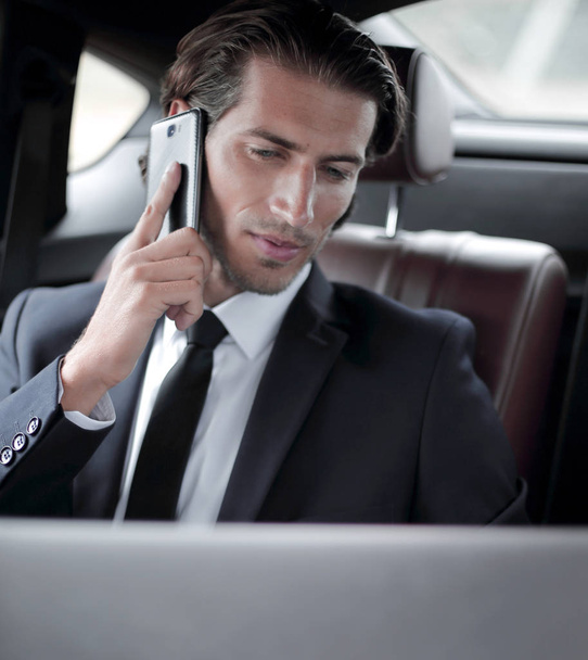 Knappe zakenman gebruik mobiele telefoon in de auto. - Foto, afbeelding