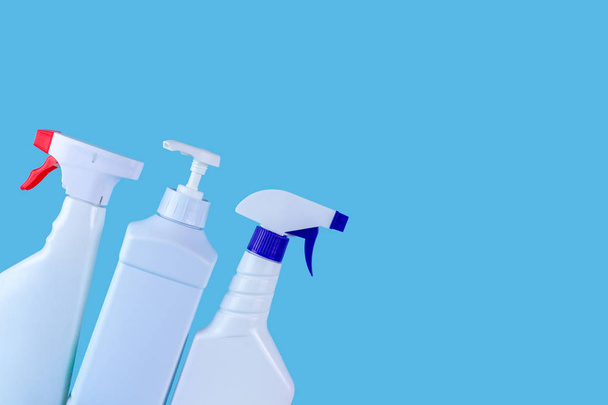 Bouteille et sprays pour nettoyer la maison sur un fond bleu. Produits de nettoyage, espace de copie
 - Photo, image