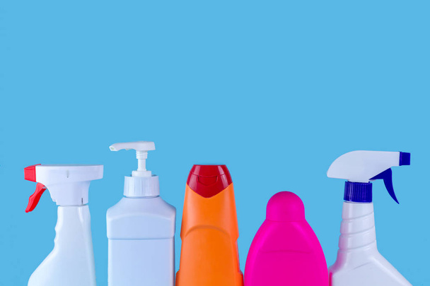 Various bottles and sprays for cleaning the house on a blue background. Cleaning concept, copy space - Фото, изображение