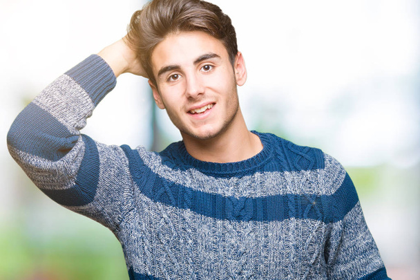 Young handsome man over isolated background Smiling confident touching hair with hand up gesture, posing attractive - Foto, afbeelding