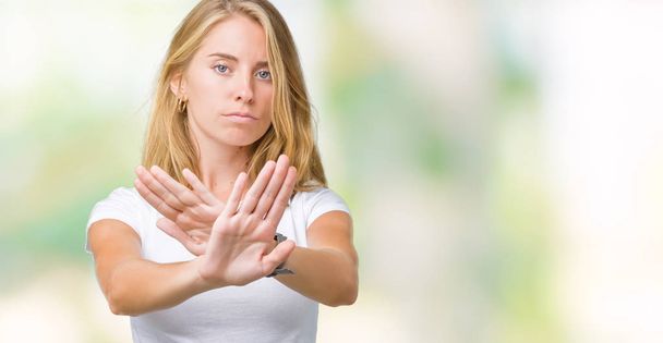 Beautiful young woman wearing casual white t-shirt over isolated background Rejection expression crossing arms and palms doing negative sign, angry face - Foto, immagini