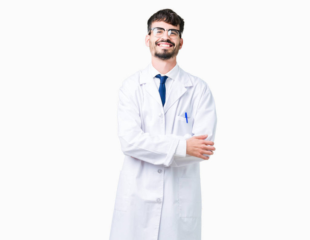 Człowiek młody naukowiec profesjonalne sobie biały płaszcz na na białym tle szczęśliwy twarz uśmiechający się z skrzyżowane ręce patrząc na kamery. Pozytywną osobą. - Zdjęcie, obraz