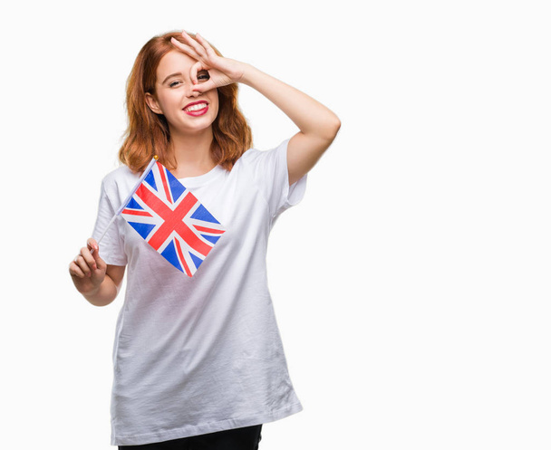 Nuori kaunis nainen tilalla lippu yhdistyneen kuningaskunnan yli eristetty tausta onnellinen kasvot hymyillen tekee ok merkki käsin katsellen sormien läpi
 - Valokuva, kuva