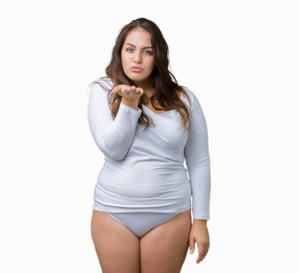 Beautiful plus size young overwight woman wearing white underwear over isolated background looking at the camera blowing a kiss with hand on air being lovely and sexy. Love expression. - Photo, Image
