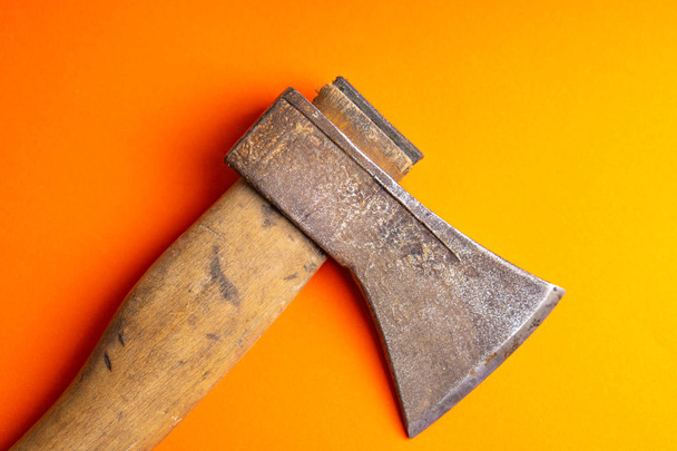 The old ax lies on the ground. Old ax with wooden handle on a bright red orange purple background top view. - Fotografie, Obrázek