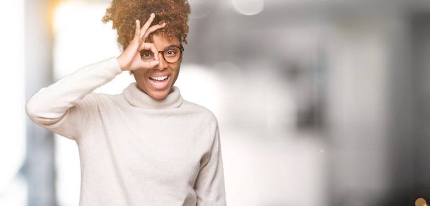 Gyönyörű fiatal afrikai-amerikai nő szemüveg elszigetelt háttérben ok gesztus mosolyogva, szemmel nézegette ujjak boldog arc kézzel át. - Fotó, kép