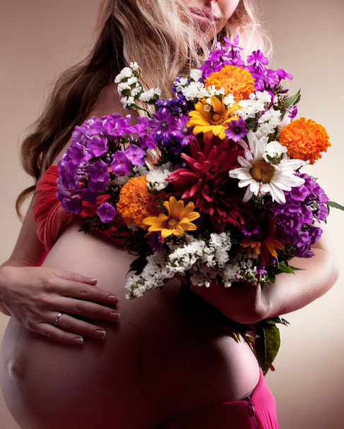 Pregnant woman holding spring flowers - Fotoğraf, Görsel