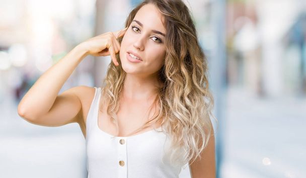 Young beautiful blonde woman over isolated background smiling doing phone gesture with hand and fingers like talking on the telephone. Communicating concepts. - Foto, imagen