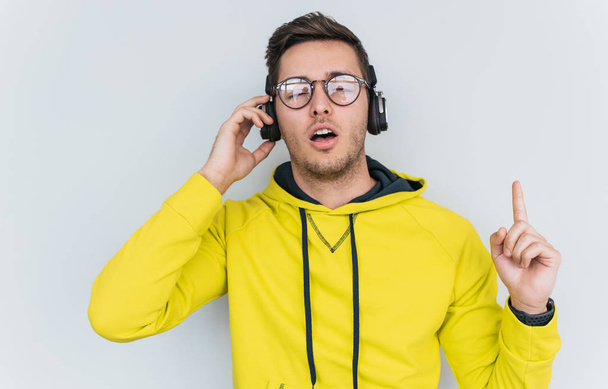 young male with relaxed expression wearing yellow hoodie with headphones  - Φωτογραφία, εικόνα