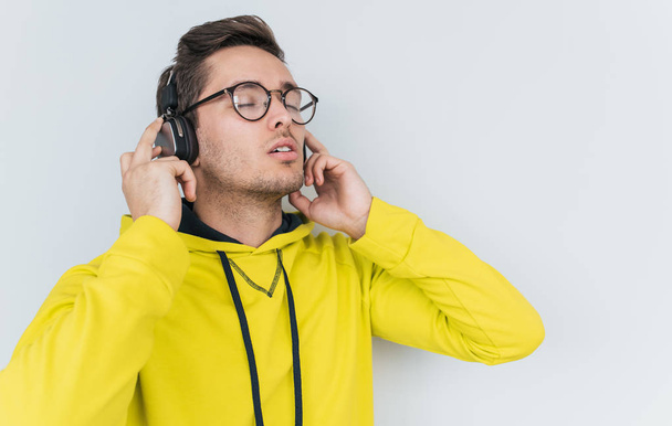 Portrait of male wearing in yellow hoodie with headphones isolated on white background - Φωτογραφία, εικόνα