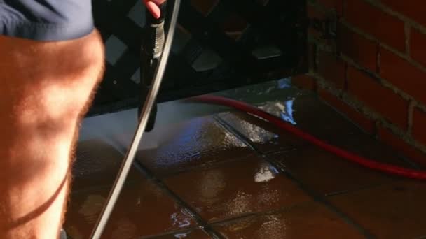 Samec čistí venkovní keramické dlažby s vysokým tlakem vody podložka. Teplé počasí nutí lidi začínající jarní úklid. - Záběry, video