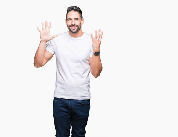 Mladý muž nosí ležérní bílé tričko izolované pozadí zobrazení a ukázal prsty číslo devět, zatímco s úsměvem a spokojené. - Fotografie, Obrázek