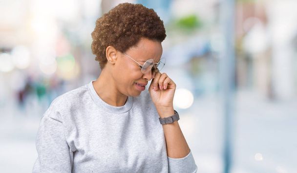 Νέοι όμορφη αφρικανική αμερικανική γυναίκα που φοράει γυαλιά πέρα από το απομονωμένο υπόβαθρο με θλιβερή έκφραση που καλύπτουν το πρόσωπο με τα χέρια ενώ κλαίει. Έννοια της κατάθλιψης. - Φωτογραφία, εικόνα