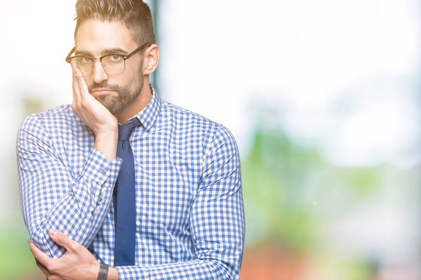 Young business man wearing glasses over isolated background thinking looking tired and bored with depression problems with crossed arms. - Photo, Image