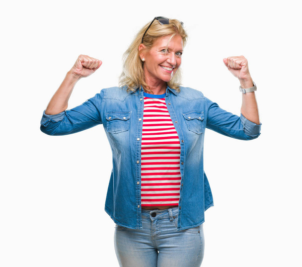 Femme blonde du moyen âge sur fond isolé montrant les muscles des bras souriant fier. Concept de fitness
. - Photo, image