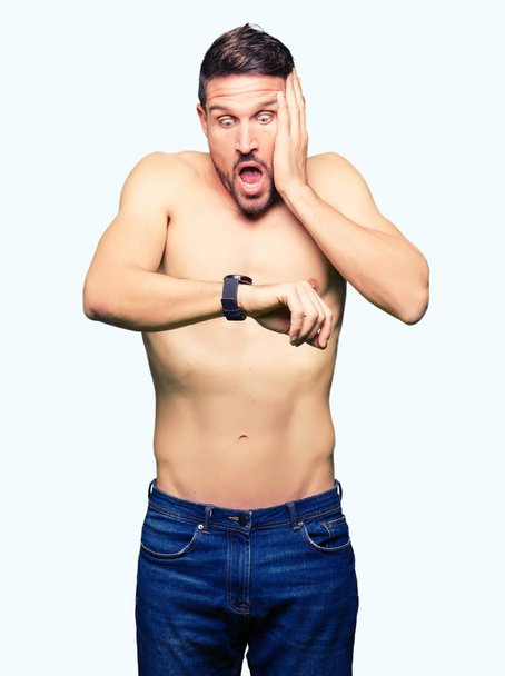Komea paidaton mies näyttää alasti rinnassa Katsella kellon aikaa huolissaan, pelkää saada myöhään
 - Valokuva, kuva