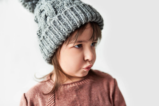 little girl with blowing kiss in winter warm gray hat, wearing sweater  - Foto, Imagem