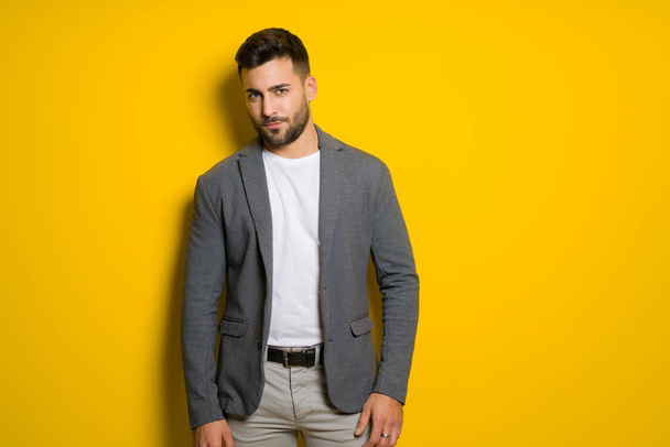 Young handsome man possing and modeling over yellow isolated background - Photo, Image