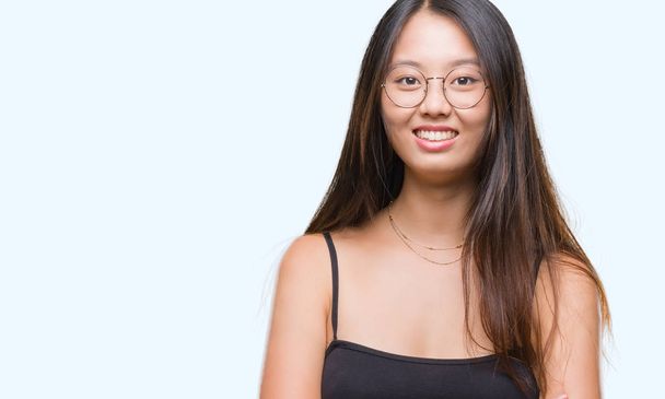 junge asiatische Frau mit Brille über isoliertem Hintergrund glücklich lächelnd mit verschränkten Armen in die Kamera blickend. positive Person. - Foto, Bild