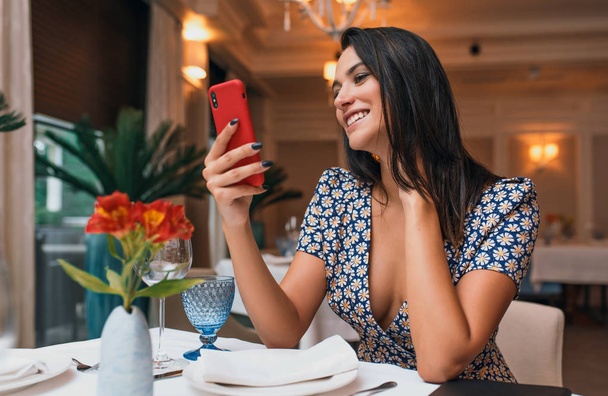 young woman sitting in restaurant and using smartphone - Foto, Imagem