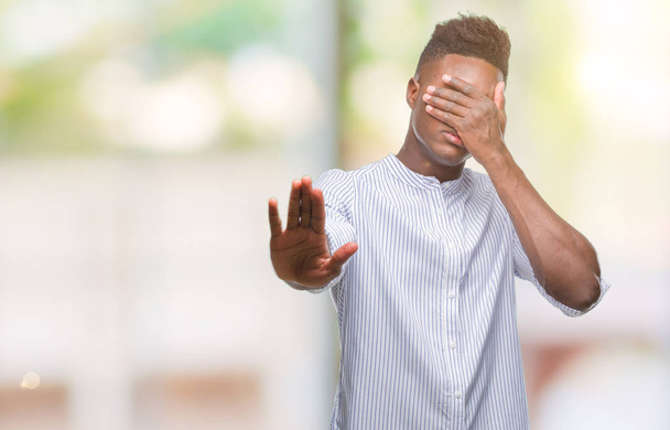 Young african american man over isolated background covering eyes with hands and doing stop gesture with sad and fear expression. Embarrassed and negative concept. - Foto, imagen
