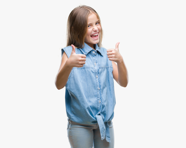 Young beautiful girl over isolated background success sign doing positive gesture with hand, thumbs up smiling and happy. Looking at the camera with cheerful expression, winner gesture. - Фото, зображення