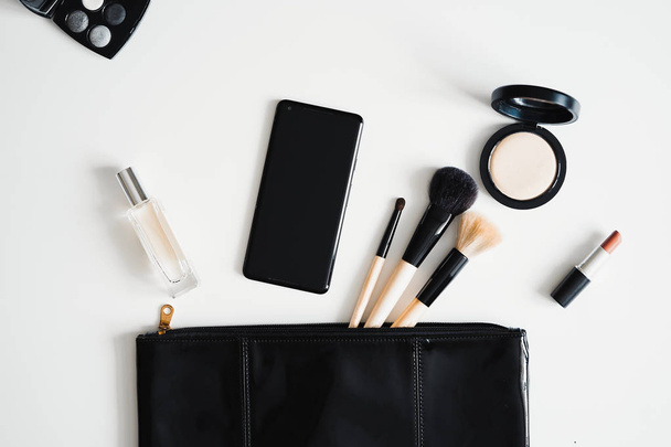 Flat lay of cosmetics, facial care products, make up equipment, clutch bag and mobile phone. - Φωτογραφία, εικόνα