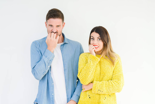 Young beautiful couple togheter over isolated background looking stressed and nervous with hands on mouth biting nails. Anxiety problem. - Valokuva, kuva