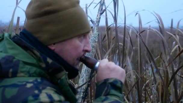 Hunter s zbraň puška oblečený v maskování volání kachny s křepelka potrubí - Záběry, video