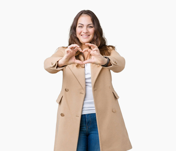プラスサイズの若い女性は美しい背景ハート記号と手で形を示す愛の笑顔を分離で冬のコートを着ています。ロマンチックな概念. - 写真・画像