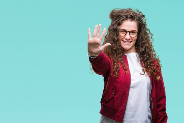 Beautiful brunette curly hair young girl wearing jacket and glasses over isolated background showing and pointing up with fingers number five while smiling confident and happy. - Photo, Image
