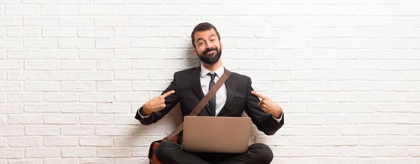 Бизнесмен со своим ноутбуком сидит на полу гордый и самодовольный в любви концепции
 - Фото, изображение