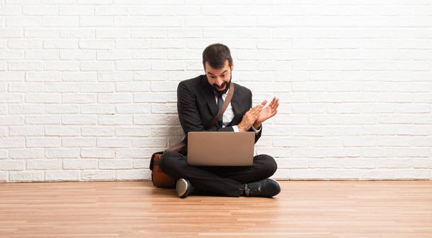 Бізнесмен зі своїм ноутбуком сидить на підлозі аплодуючи після презентації на конференції
 - Фото, зображення