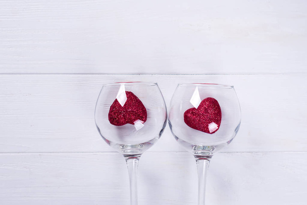 白い木製の背景は、フラット レイアウト上ガラスとバレンタインの日に赤いハートをワインします。 - 写真・画像