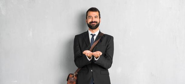 Businessman with beard holding copyspace imaginary on the palm to insert an ad - Fotografie, Obrázek