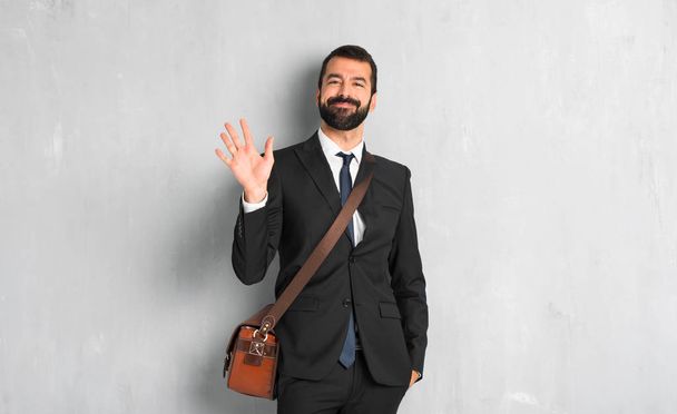 Businessman with beard saluting with hand with happy expression - Photo, Image