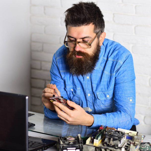 Master of computers. Bearded hipster works on fixing digital hardware. Assemblying of electronic devices. Bearded man repair circuit board. Engineer or technician at work. Engineering and computer - Фото, изображение