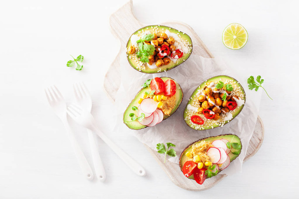 avocado boats stuffed with hummus, tomatoes, radish, roasted chickpea - 写真・画像