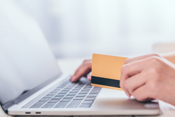 selective focus of credit card in hand of woman using laptop - Foto, Bild