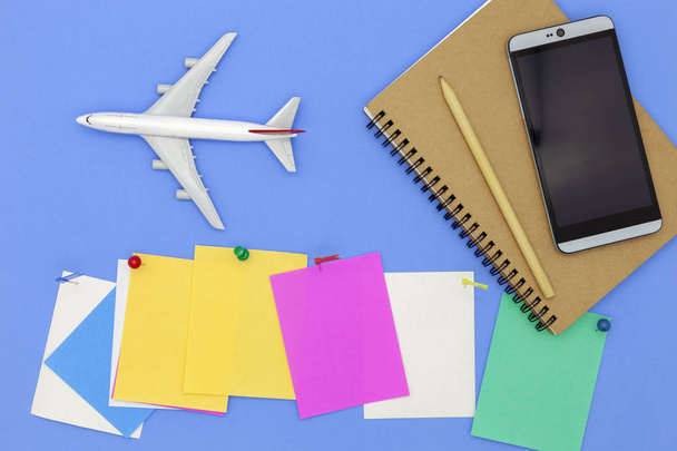 Airplane model with smartphone and paper note on blue background. - Photo, Image