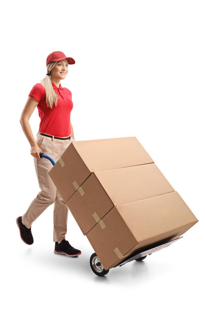Full length shot of a female delivering boxes with a hand truck isolated on white background - Fotó, kép