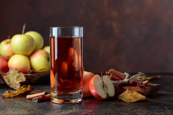 Un vaso de jugo de manzana o sidra con manzanas jugosas y palitos de canela en una mesa de cocina
. - Foto, imagen