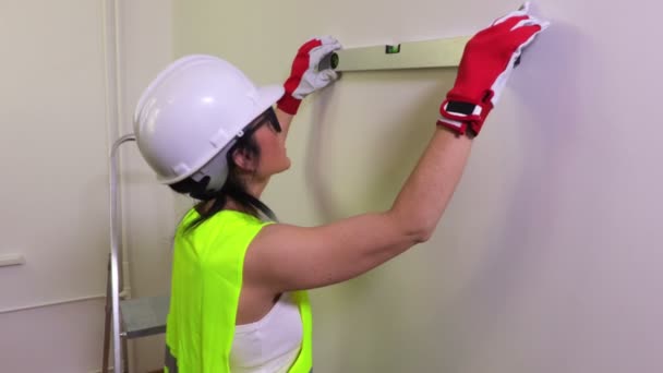Vrouw bouwvakker met waterpas in de buurt van de muur - Video