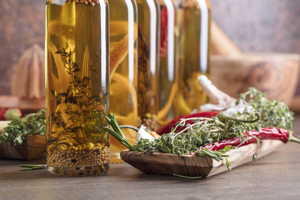 Olívaolaj, egy régi fából készült asztal üveg. Olívaolaj a különböző fűszerek és fűszernövények. - Fotó, kép