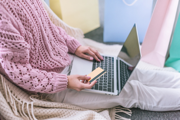 Ausgeschnittene Ansicht einer Frau mit Kreditkarte in der Nähe des Laptops beim Online-Einkauf - Foto, Bild