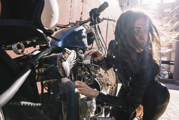 Mujer que revisa motocicleta en la calle
 - Foto, imagen