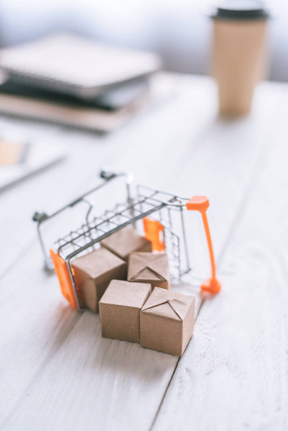 selective focus of toy of packages near decorative cart on wooden desk  - 写真・画像