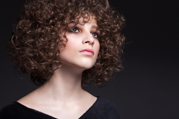 Portrait of a beautiful teen girl with natural make-up and afro curls. On a black background. - Photo, Image