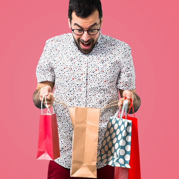 Pembe bir arka plan üzerinde alışveriş çantası ile gözlüklü yakışıklı adam - Fotoğraf, Görsel