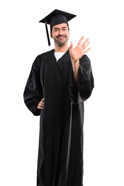 Mann an seinem Universitätsabschluss salutiert mit fröhlichem Gesichtsausdruck - Foto, Bild